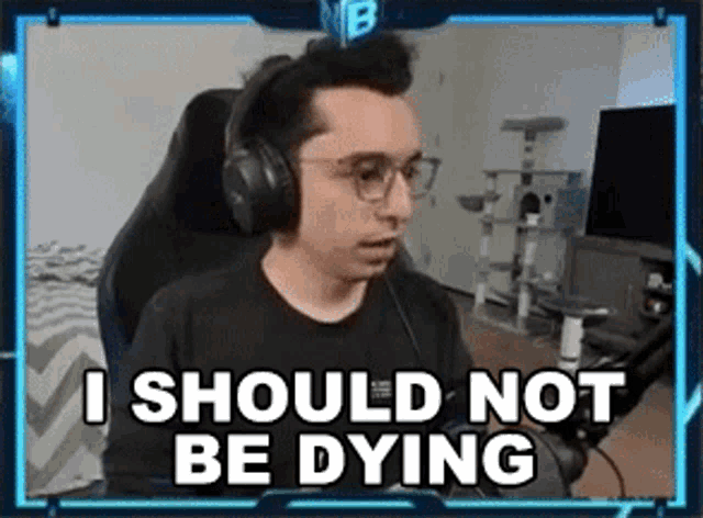 a man wearing headphones and glasses is sitting in a gaming chair and saying `` i should not be dying '' .