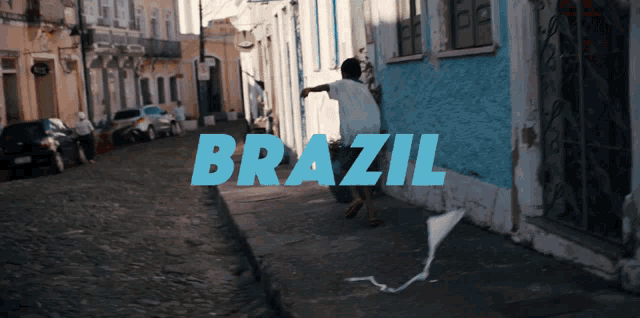 a person flying a kite on a street with the word brazil written in blue