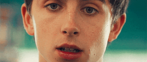 a close up of a young man 's face with blue eyes and freckles