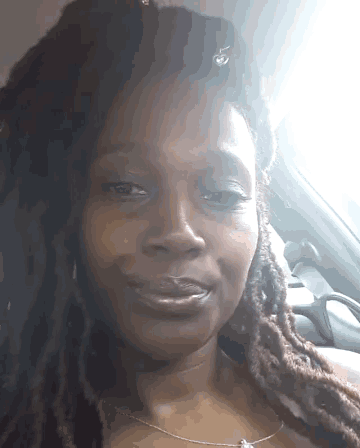 a woman with dreadlocks and a necklace is smiling for the camera