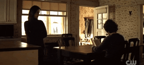 two people are sitting at a table with a cw logo in the corner