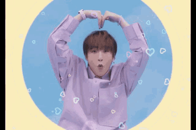 a man in a purple shirt is making a heart with his hands
