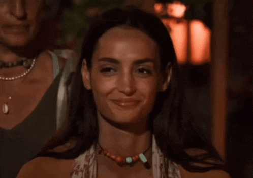 a woman wearing a necklace with beads on it smiles