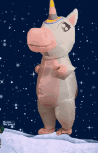 an inflatable unicorn is standing on a snowy hill