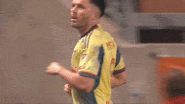 a man wearing a yellow jersey with a red bull on it