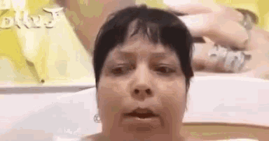 a woman is sitting in a bathtub with her mouth open and looking at the camera .