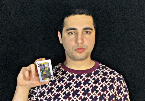 a man in a patterned shirt is holding a joker card in his hand