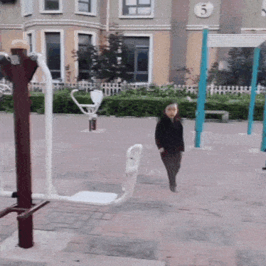 a little girl walking in front of a building with the number 5 on the side