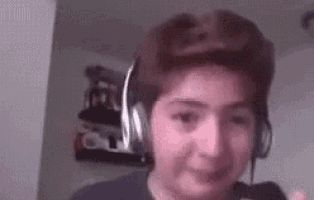 a young boy wearing headphones and a hat is looking at the camera .