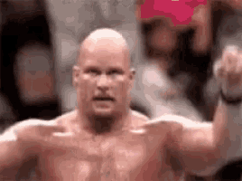 a bald man without a shirt is raising his fist in the air in front of a crowd .