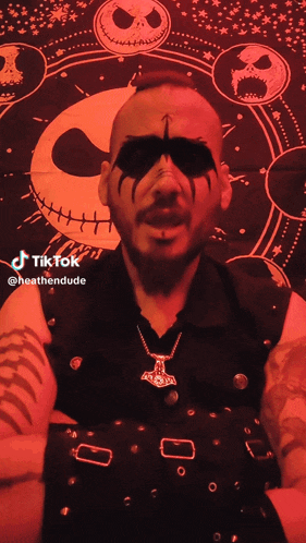 a man wearing a black vest and a necklace has a tiktok account named heathendude