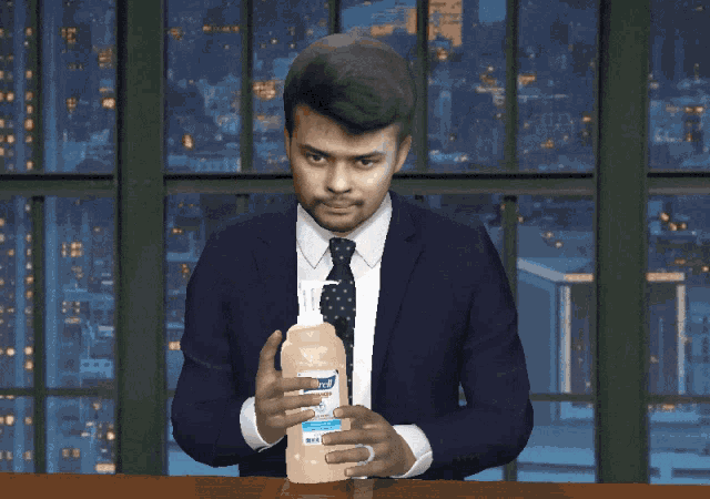 a man in a suit and tie is holding a bottle of clorox hand sanitizer