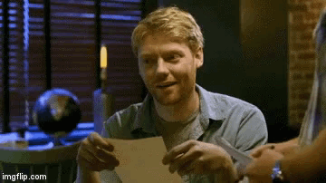 a man is smiling while holding a piece of paper in front of him .