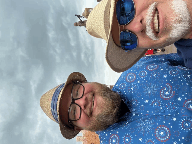 two men wearing hats and sunglasses pose for a photo