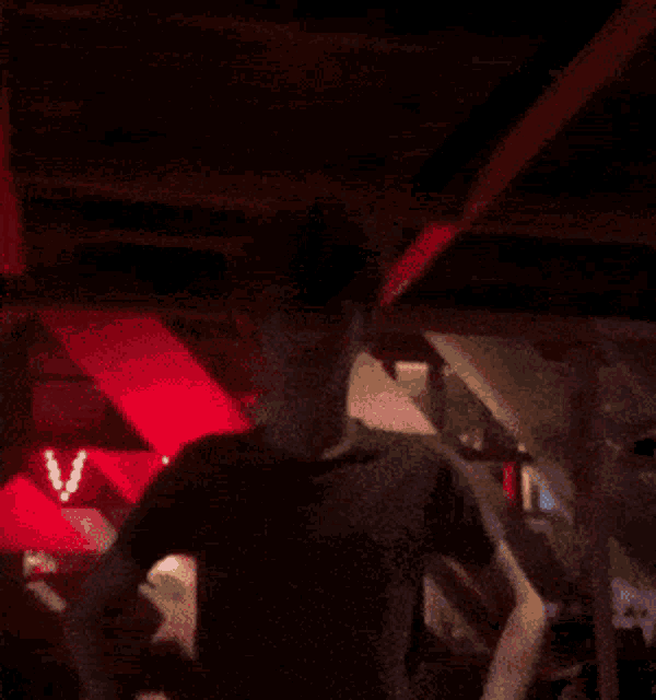 a man standing in a dark room with a red sign that says v