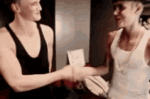 two men are shaking hands in a room .