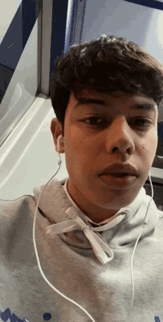 a young man wearing ear buds and a grey hoodie