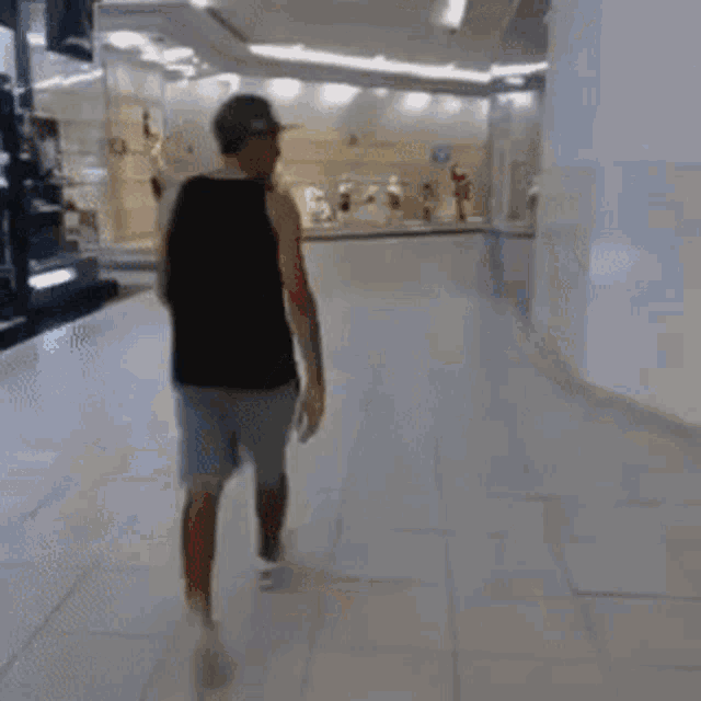 a man wearing a red hat is walking through a shopping mall