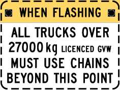 a yellow sign that says when flashing all trucks over 2700 kg licensed gvw must use chains beyond this point