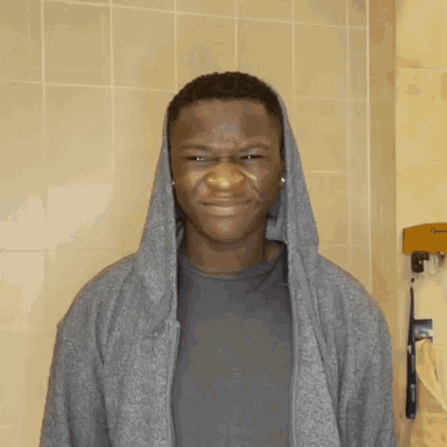 a young man wearing a hooded jacket looks at the camera