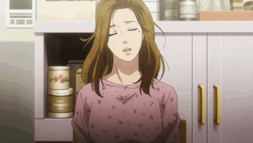 a woman in a pink shirt with letters on it is sitting in a kitchen
