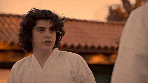 a young man with curly hair wearing a white kimono