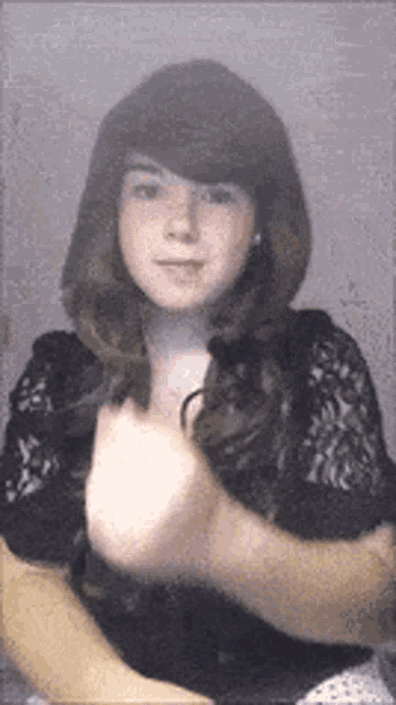 a woman in a black lace top is making a funny face .