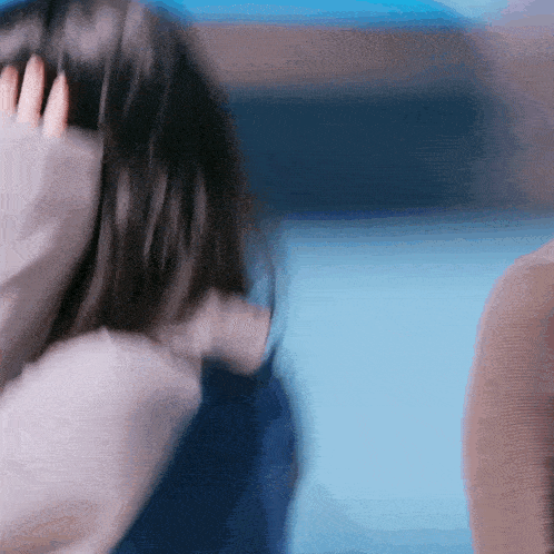 a woman is covering her ears with her hand while a man looks on .