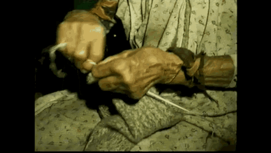 an older woman is knitting a sweater with a pair of knitting needles .