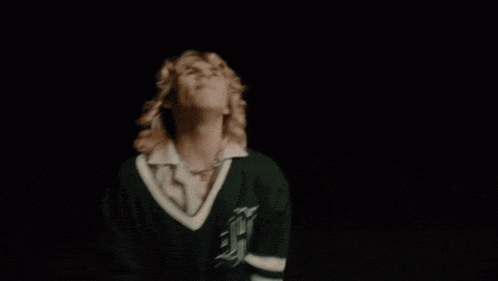 two men are dancing in a dark room with their hands in the air