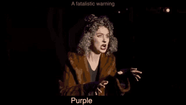 a woman in a purple wig is standing in a dark room with her mouth open .