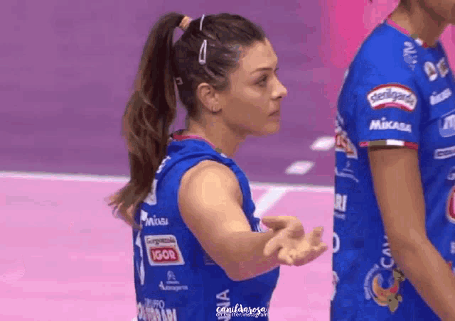 a female volleyball player wearing a blue jersey with logos on it