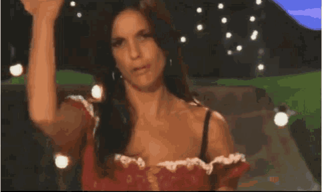 a woman in a red dress is standing in front of a row of lights