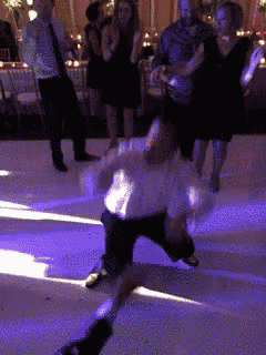 a group of people dancing on a dance floor with purple lights