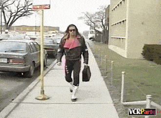 a man walking down a sidewalk with a sign that says vcrparty in the corner