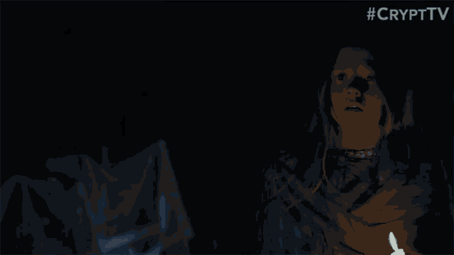 a young girl is wrapped in a blue blanket and holding a candle in the dark .