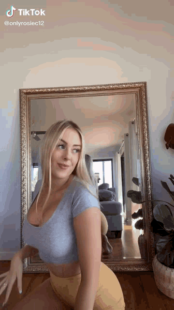 a woman is kneeling in front of a large mirror .