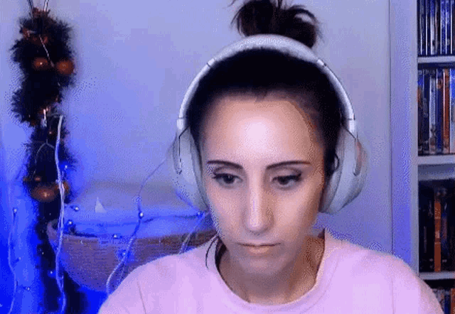 a woman wearing headphones and a pink shirt is sitting in front of a christmas tree .