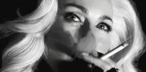a black and white photo of a woman smoking a cigarette