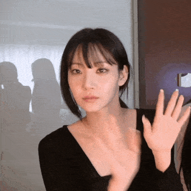 a woman in a black top waves her hand