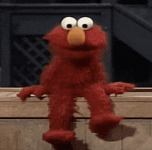 elmo the sesame street character is sitting on a wooden railing .