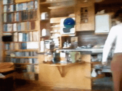 a blurred image of a person standing in front of a bookcase