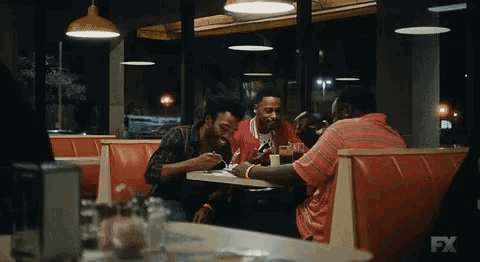 a group of men sit at a table in a diner with fx written on the bottom of the screen