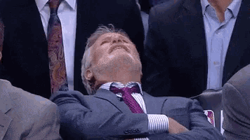 a man in a suit and tie is sleeping in the stands during a game