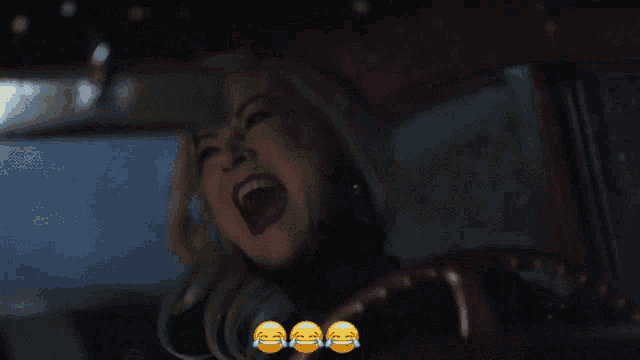 a woman is laughing in a car with three smiley faces on the steering wheel