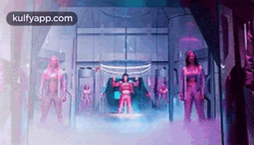 a group of people are standing in a room with a purple light coming out of the ceiling .