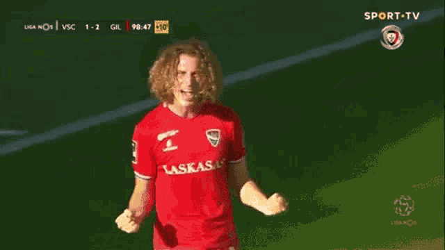 a soccer player wearing a red lakasa jersey is celebrating a goal