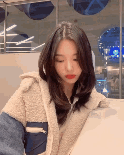 a woman wearing a sherpa jacket and red lipstick