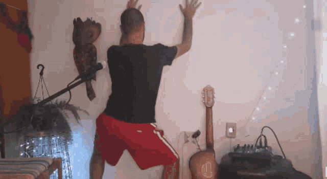 a man in red shorts is leaning against a wall with his arms outstretched
