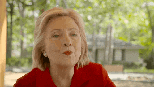 a woman in a red shirt blows a kiss at the camera